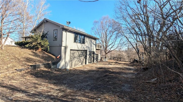 view of property exterior with dirt driveway and an attached garage