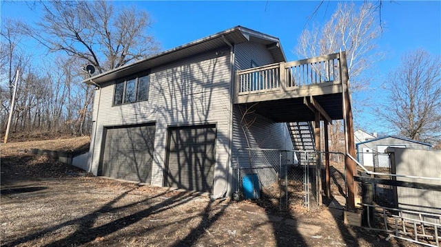 back of property with driveway, stairway, an attached garage, and a wooden deck