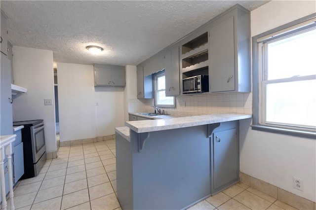 kitchen featuring open shelves, stainless steel electric stove, gray cabinets, light countertops, and a peninsula