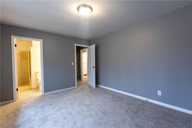 unfurnished bedroom featuring baseboards, carpet flooring, and ensuite bathroom