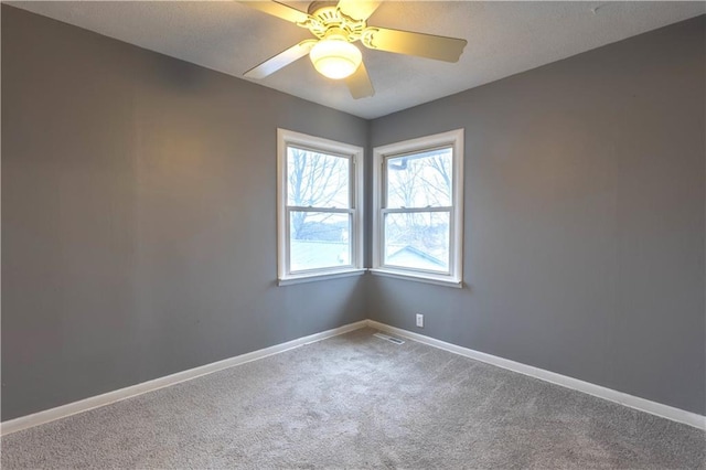 empty room featuring carpet, ceiling fan, a textured ceiling, and baseboards