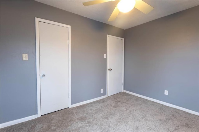 carpeted empty room featuring a ceiling fan and baseboards