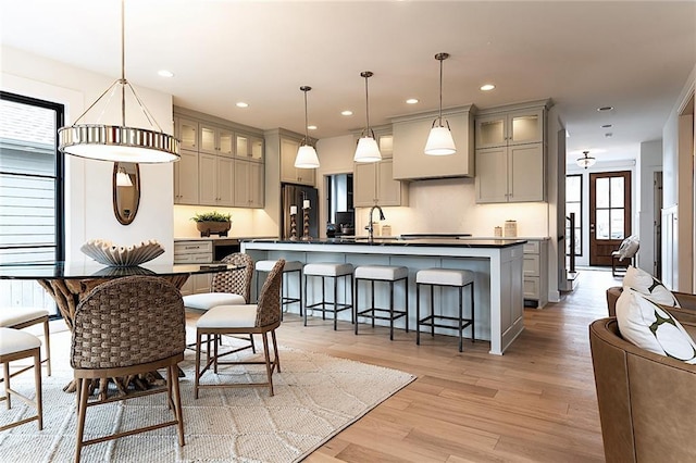 kitchen with dark countertops, gray cabinetry, light wood-style floors, fridge, and a sink