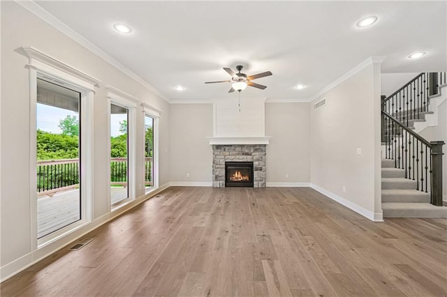 unfurnished living room featuring crown molding, visible vents, light wood-type flooring, baseboards, and stairs