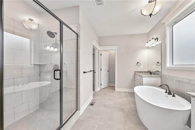 full bath featuring visible vents, baseboards, vanity, a freestanding tub, and a shower stall