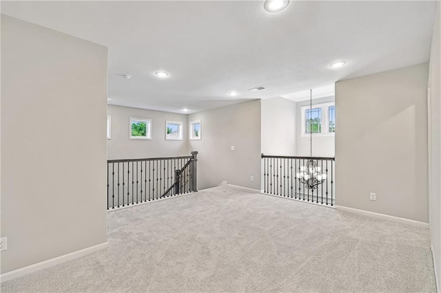 carpeted empty room featuring an inviting chandelier, visible vents, baseboards, and recessed lighting