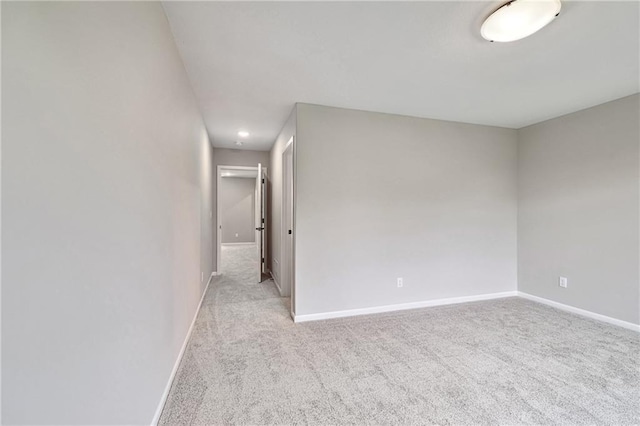 spare room featuring light carpet and baseboards