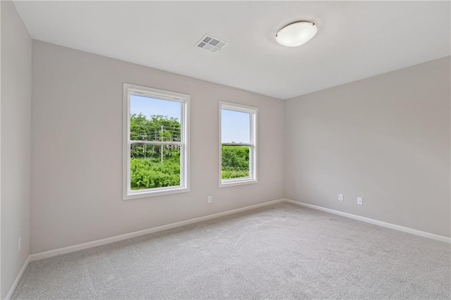 empty room with baseboards, visible vents, and carpet flooring