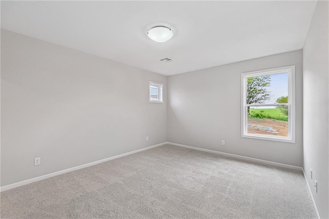 spare room with carpet flooring, visible vents, and baseboards