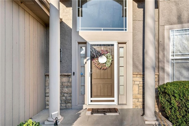 entrance to property featuring stucco siding and stone siding