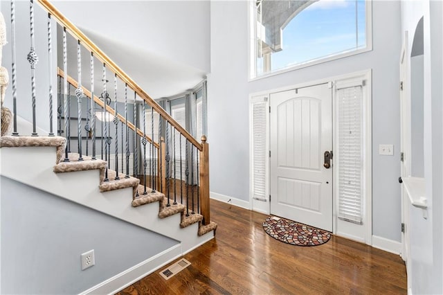 entrance foyer with visible vents, a high ceiling, wood finished floors, and stairs