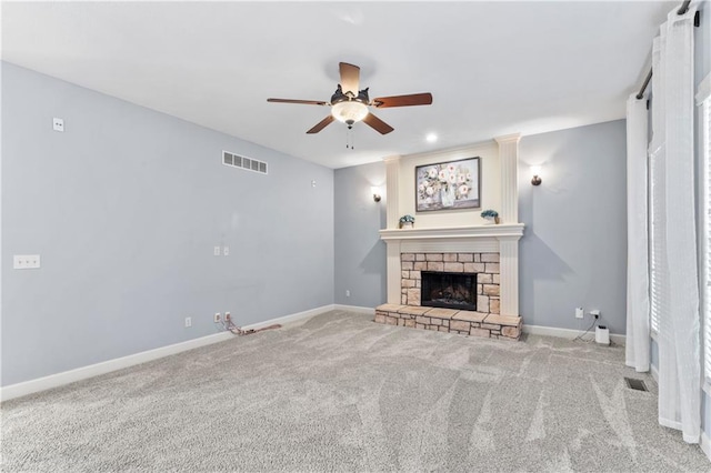 unfurnished living room featuring visible vents, carpet, a fireplace, baseboards, and ceiling fan