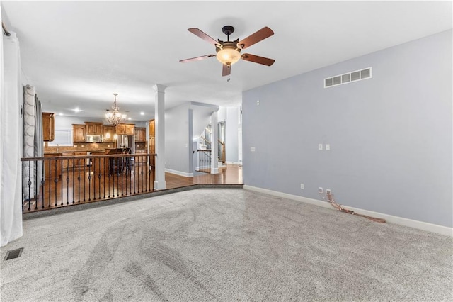 unfurnished living room featuring visible vents, baseboards, and ceiling fan with notable chandelier