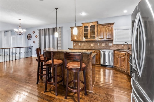 kitchen with a sink, dark wood-style floors, brown cabinets, and stainless steel appliances