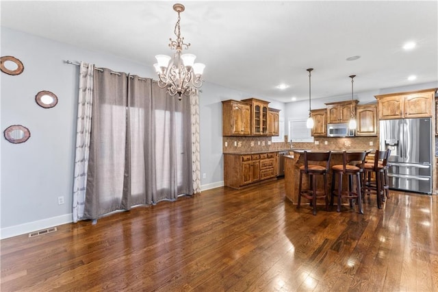 kitchen featuring visible vents, decorative backsplash, dark wood-type flooring, appliances with stainless steel finishes, and brown cabinets