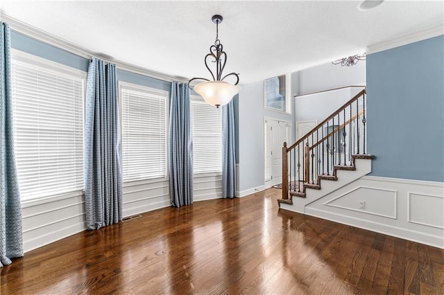 interior space featuring stairway, wood finished floors, visible vents, ornamental molding, and a decorative wall