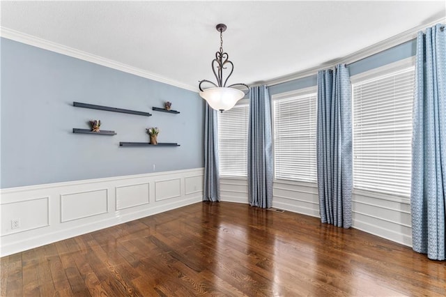 unfurnished room with a wainscoted wall, visible vents, wood finished floors, and ornamental molding