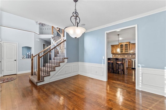 dining area with stairway, a wainscoted wall, wood finished floors, and crown molding