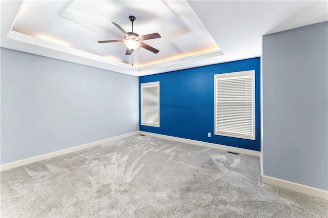 carpeted empty room with baseboards, a raised ceiling, and ceiling fan