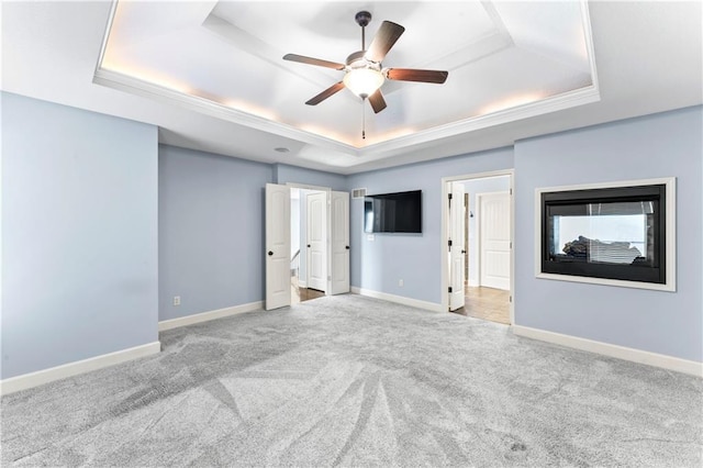 interior space featuring baseboards, a raised ceiling, carpet, and a ceiling fan