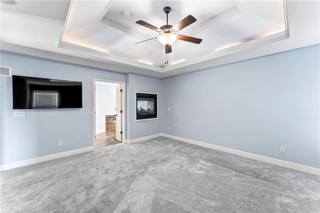 carpeted empty room with a tray ceiling, baseboards, and ceiling fan