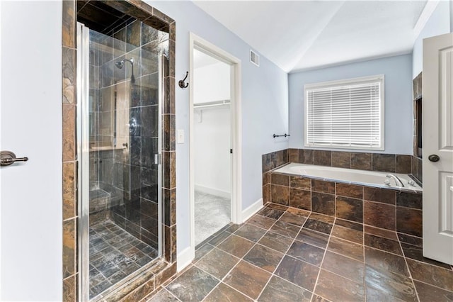 bathroom with visible vents, a shower stall, vaulted ceiling, a walk in closet, and a bath