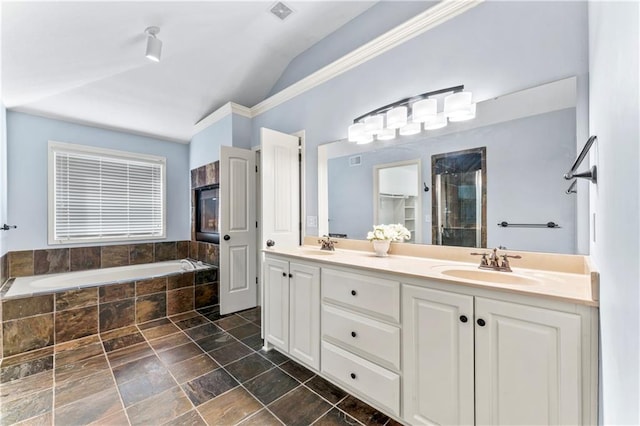 full bathroom featuring double vanity, a stall shower, a sink, vaulted ceiling, and a garden tub