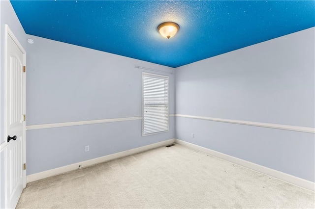 carpeted empty room featuring visible vents, baseboards, and a textured ceiling