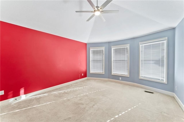 carpeted empty room with visible vents, baseboards, lofted ceiling, and a ceiling fan