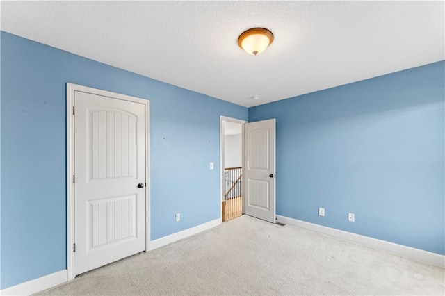 unfurnished bedroom featuring baseboards, carpet, and a textured ceiling