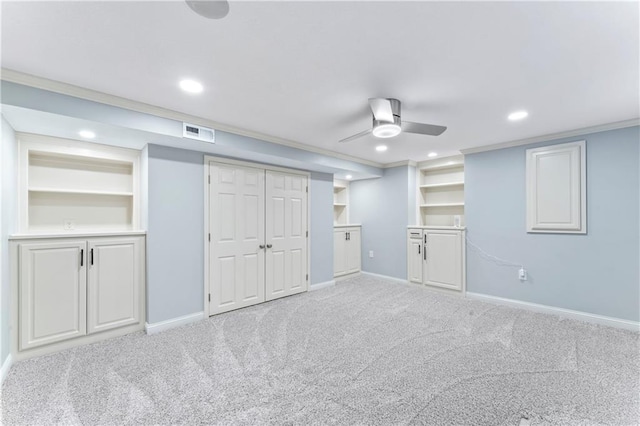 basement with built in shelves, carpet, a ceiling fan, visible vents, and baseboards