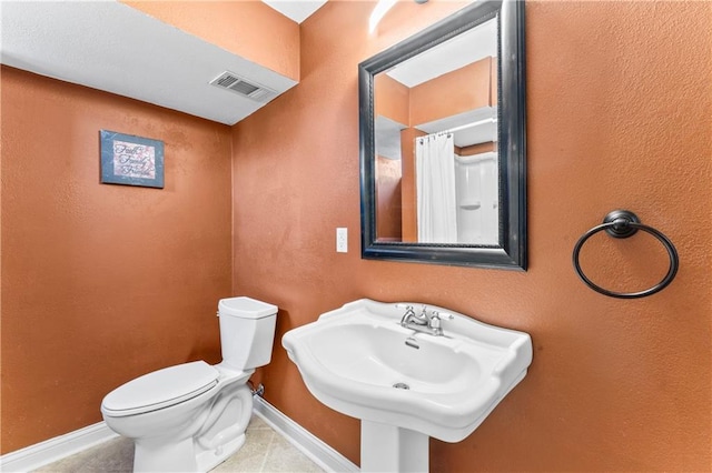 bathroom featuring visible vents, toilet, a sink, tile patterned flooring, and baseboards