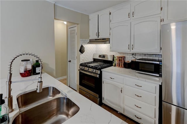 kitchen with stainless steel appliances, tasteful backsplash, white cabinets, and under cabinet range hood