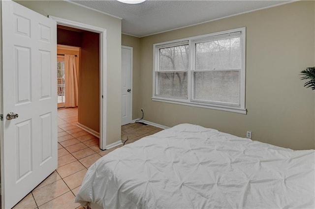 bedroom with light tile patterned floors, a textured ceiling, and baseboards