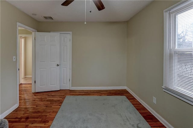 spare room with wood finished floors, visible vents, and baseboards