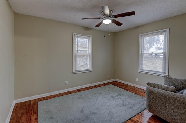 unfurnished room featuring a textured ceiling, wood finished floors, a ceiling fan, and baseboards