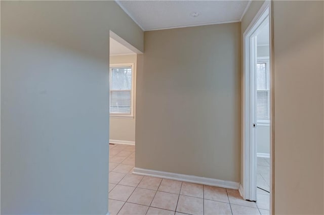 empty room with ornamental molding, light tile patterned flooring, and baseboards