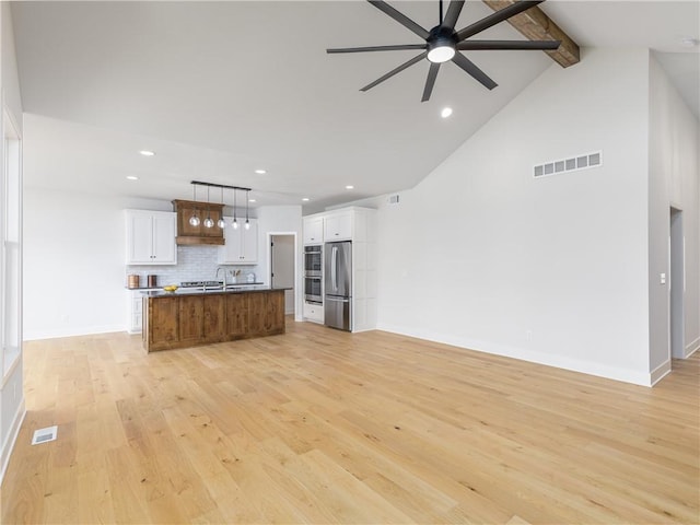 unfurnished living room featuring visible vents, beamed ceiling, a ceiling fan, and light wood finished floors