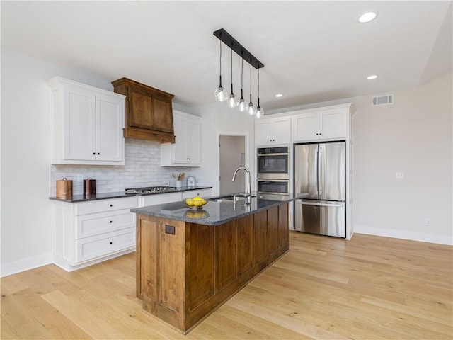 kitchen with light wood finished floors, visible vents, decorative backsplash, stainless steel appliances, and a sink