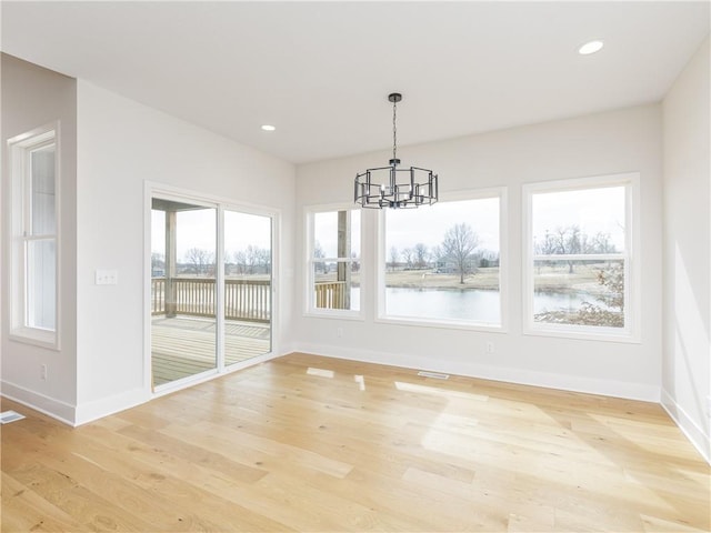 unfurnished dining area featuring a chandelier, recessed lighting, light wood-type flooring, and baseboards