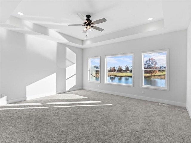 carpeted spare room with a ceiling fan, a tray ceiling, recessed lighting, and baseboards