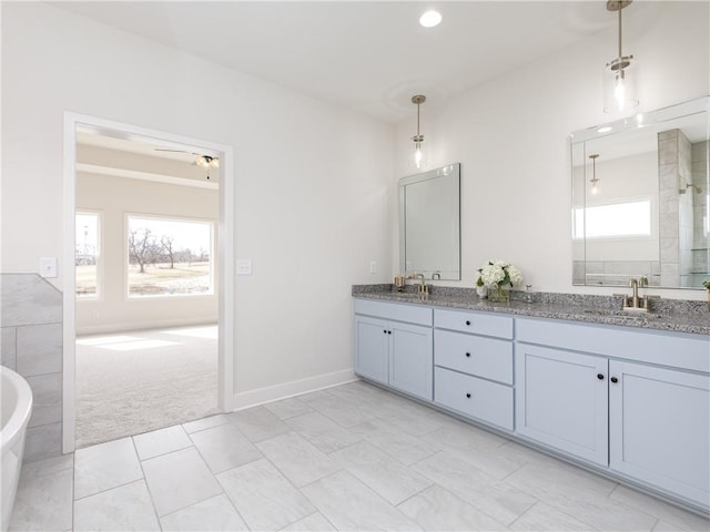 full bath with baseboards, a shower with shower door, double vanity, a freestanding bath, and a sink