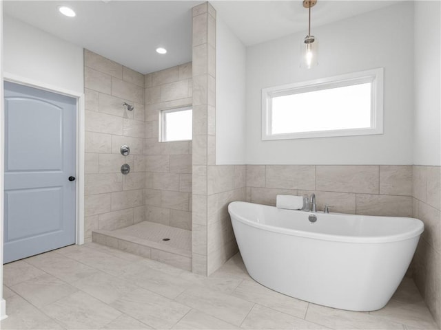 bathroom with a tile shower, plenty of natural light, and a soaking tub