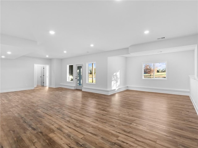 unfurnished living room with recessed lighting, plenty of natural light, and wood finished floors