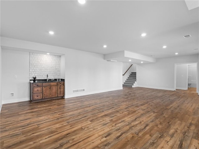 finished below grade area with recessed lighting, stairway, dark wood-type flooring, and visible vents