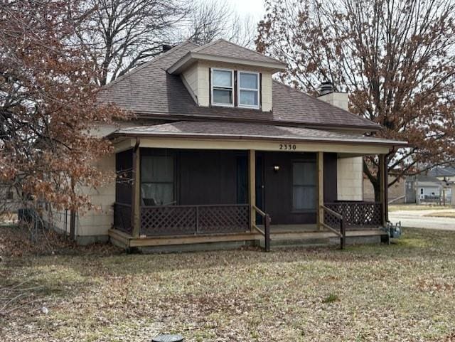 bungalow-style home with covered porch, a shingled roof, and a chimney