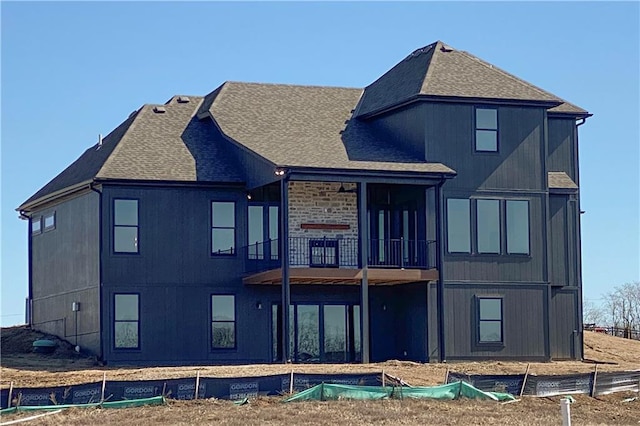 rear view of property with a balcony and a shingled roof