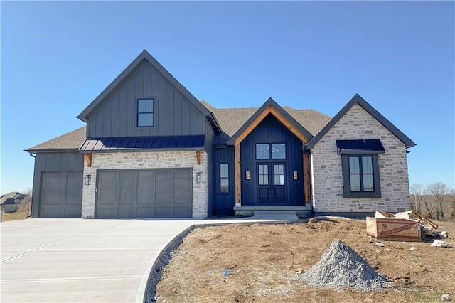 view of front of property featuring board and batten siding, an attached garage, driveway, and a standing seam roof