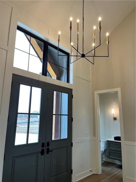 entryway with dark wood-type flooring, a high ceiling, an inviting chandelier, and a decorative wall