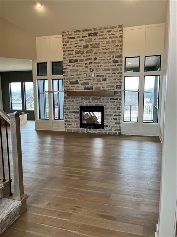 unfurnished living room featuring stairway, wood finished floors, and a fireplace